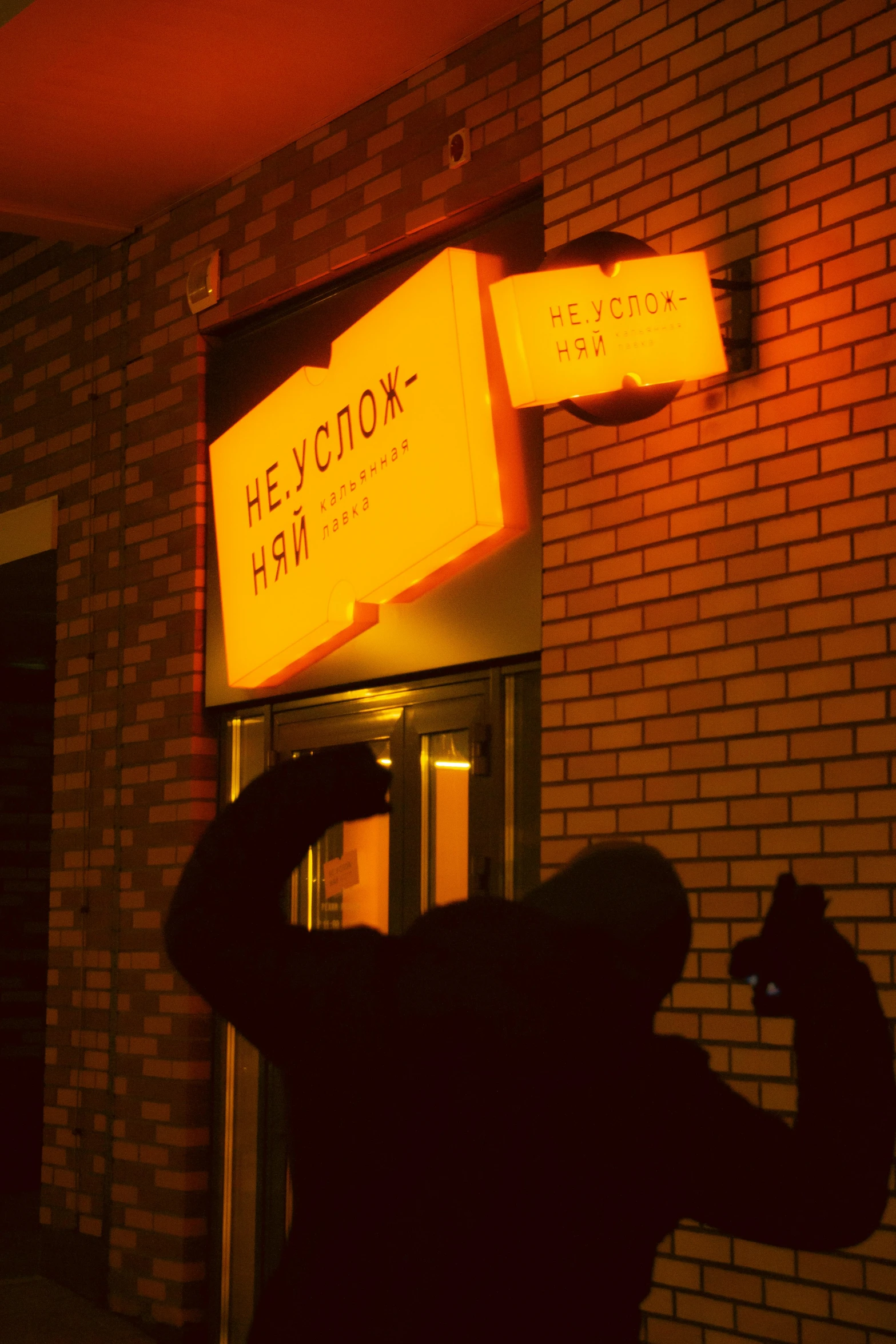 a man in front of the door of a business with a cat next to him