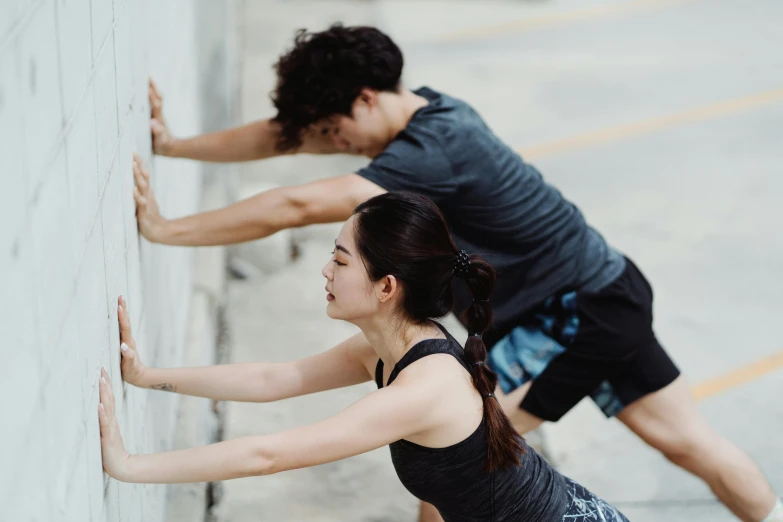 two women are leaning against the wall with their hands on each other