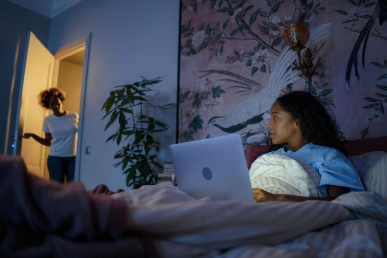 the woman is looking at her laptop in bed