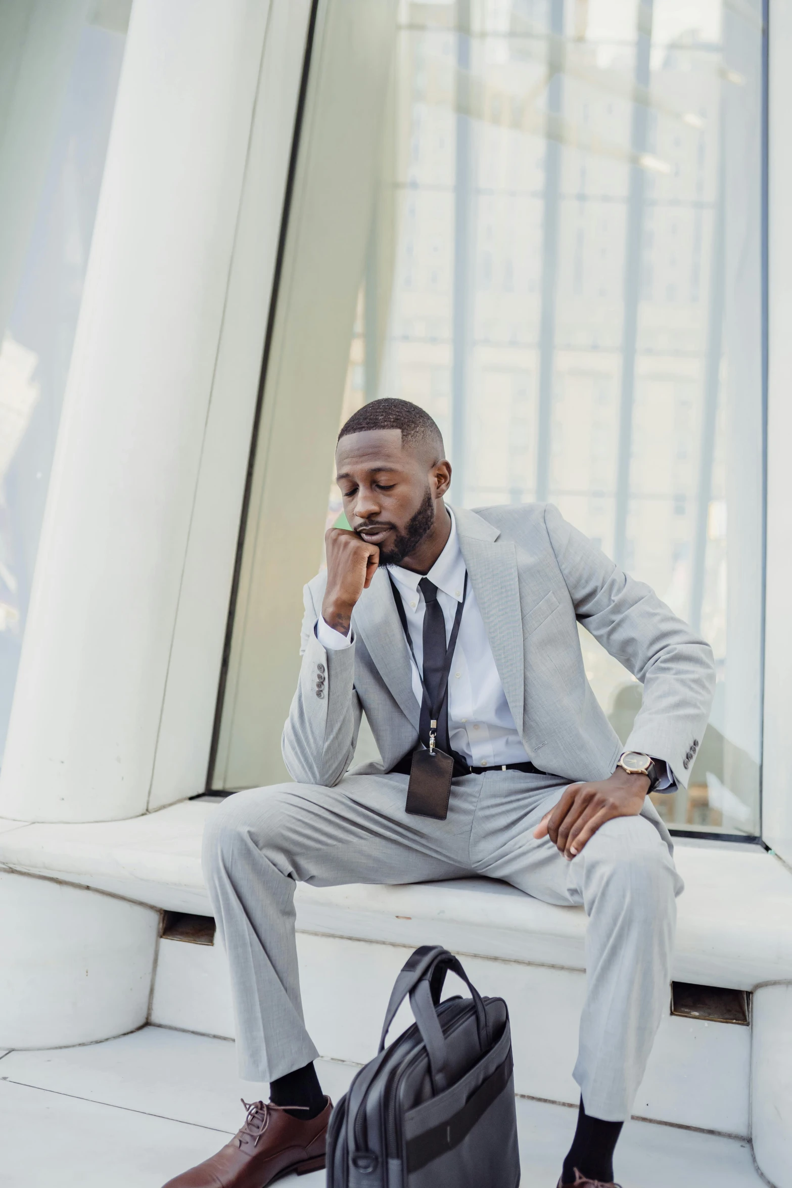 a man wearing a gray suit sitting on a bench while talking on his cell phone