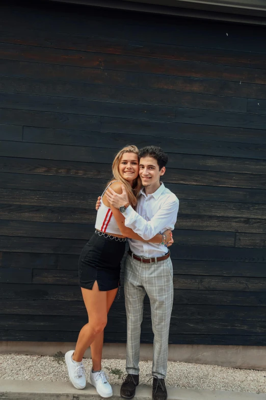 a beautiful woman standing next to a man near a building