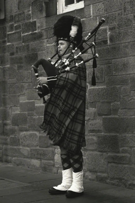 a man in plaid skirt holding bagpipes and pipes