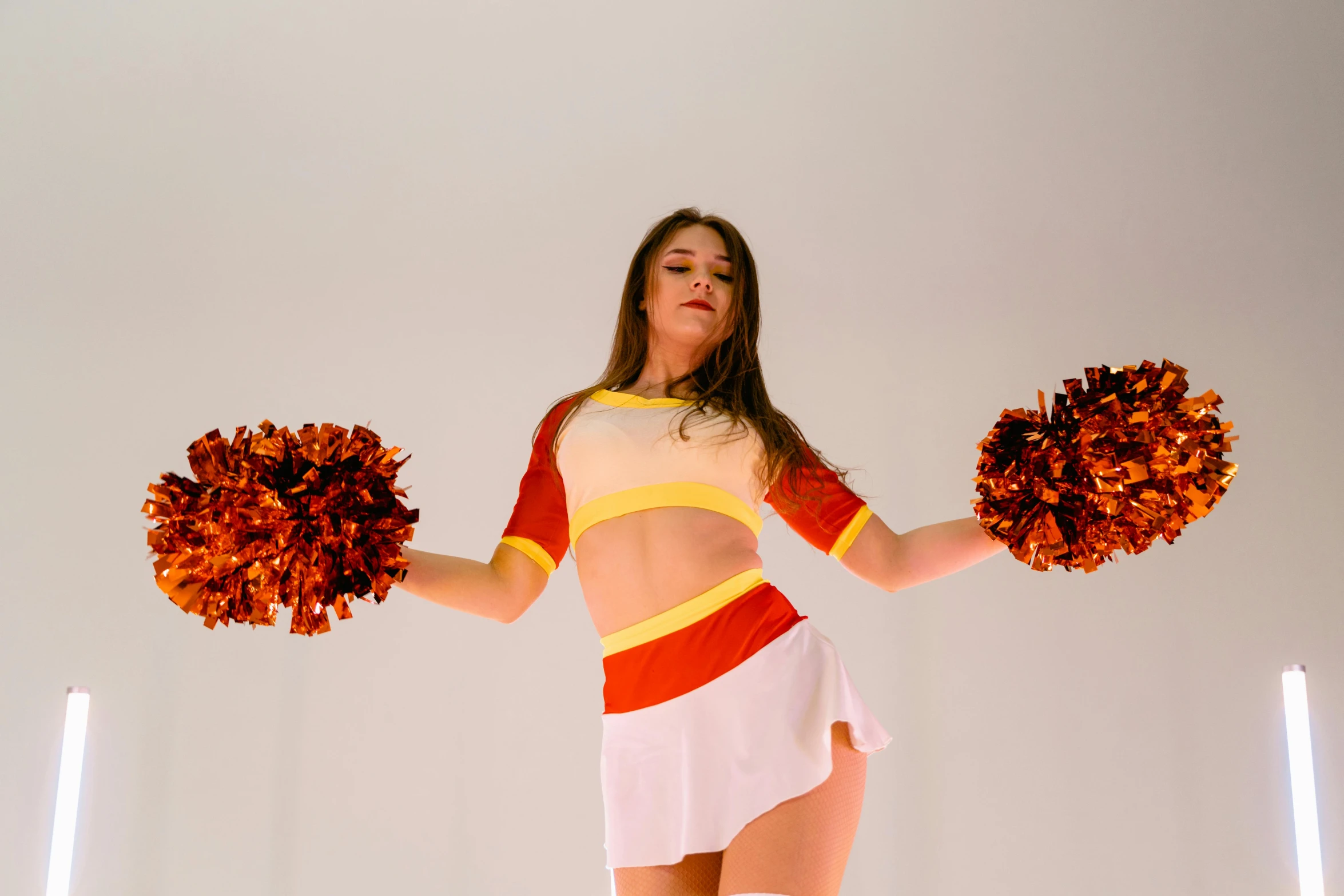 a girl wearing red, white and yellow clothes holding up three orange balls