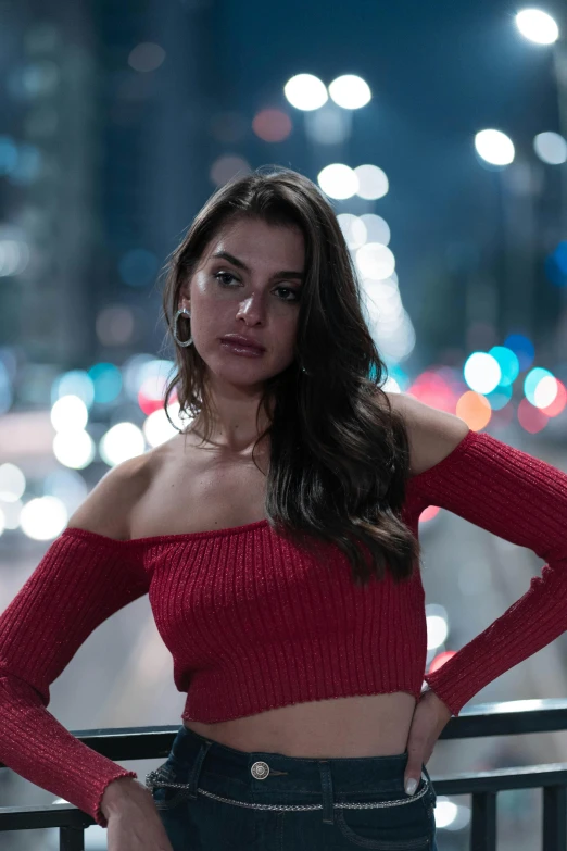 a woman in a red sweater leaning on the railing of a bridge