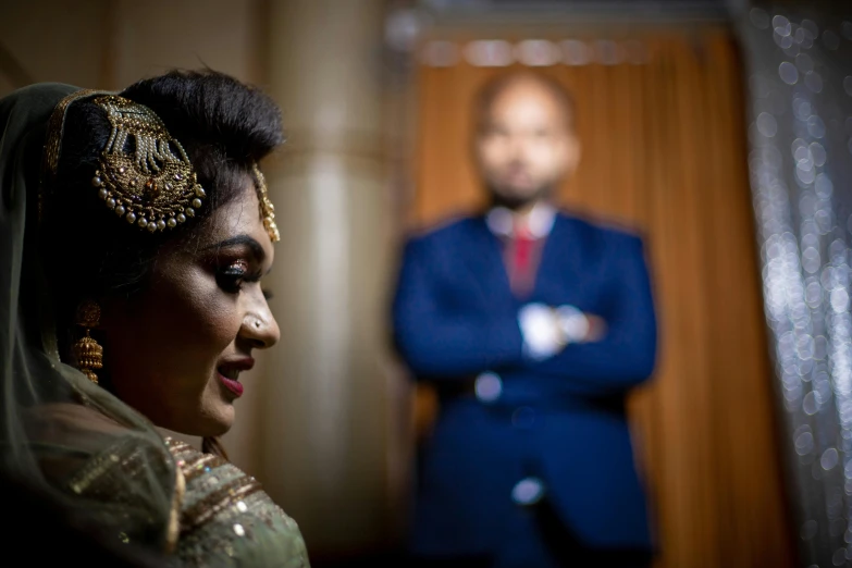 bride posing with groom in background, from back