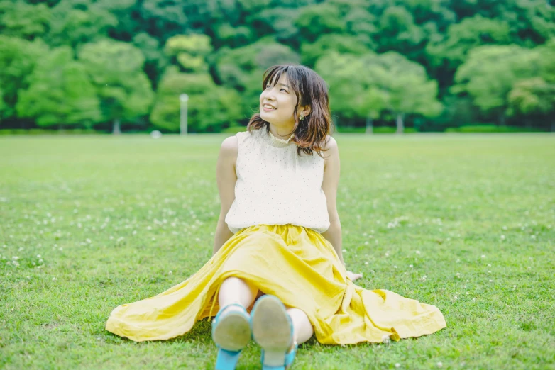 a beautiful young woman sitting in the grass in a skirt