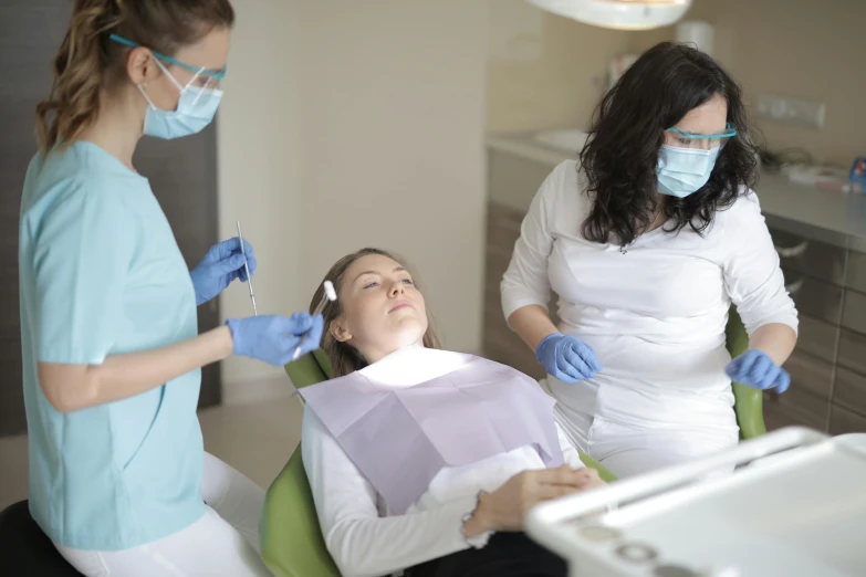 two women in the dentist's chair with a woman in a mask
