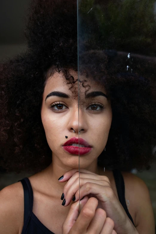 a woman with an afro standing behind a mirror