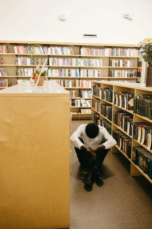 a black guy in the liry with several shelves full of books