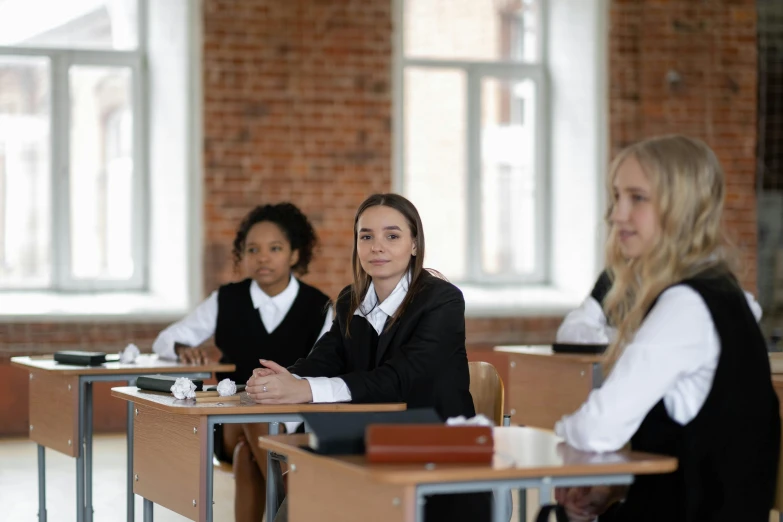 three girls are sitting in desks that are empty