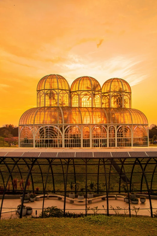 a glass house with a long curved walkway leading up to the inside