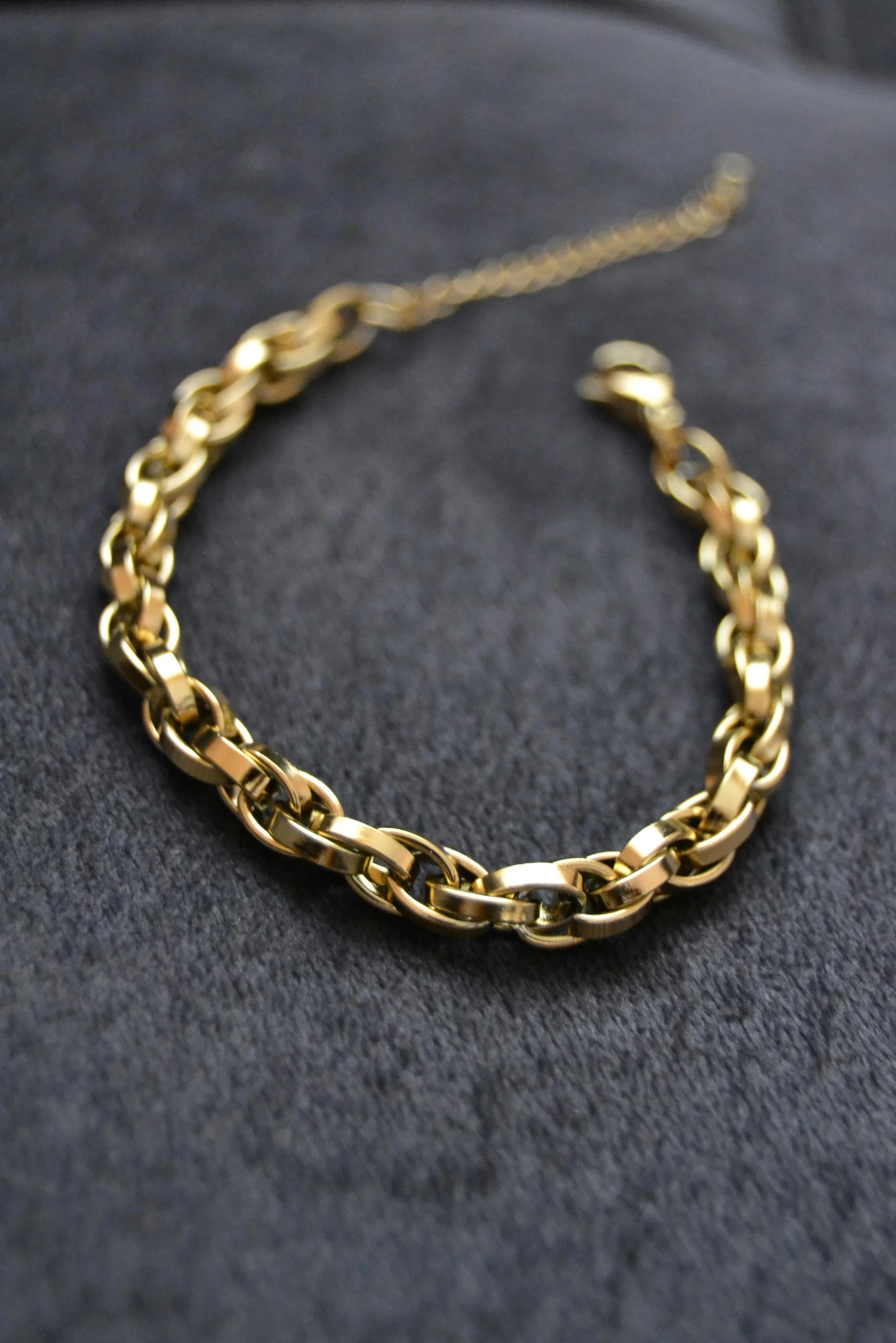 closeup of an uncut gold chain, lying on a grey surface