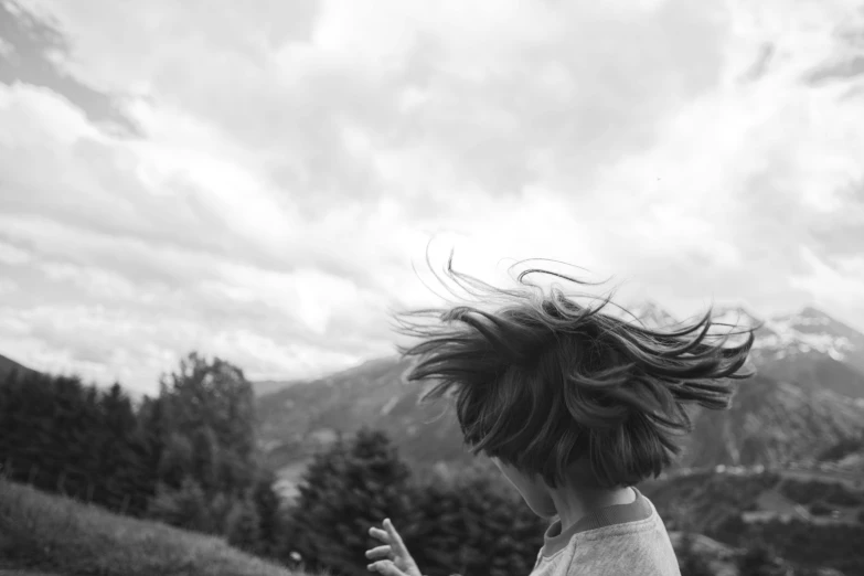 a young child tossing her hair in the wind