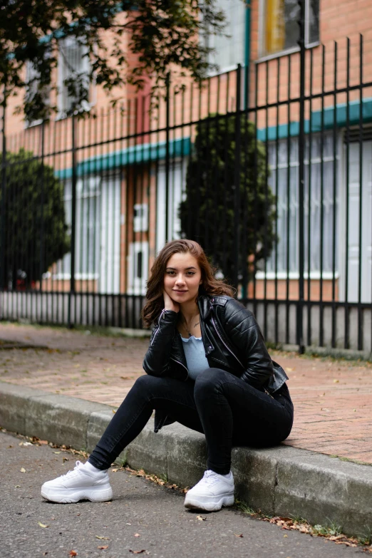 a woman is posing outside with her hand on her chin