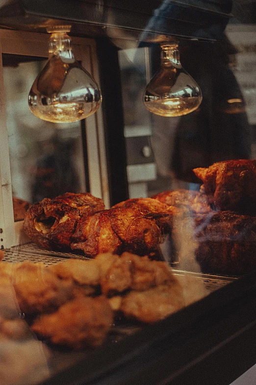 chicken, chicken drums, and other types of food are on display behind the glass