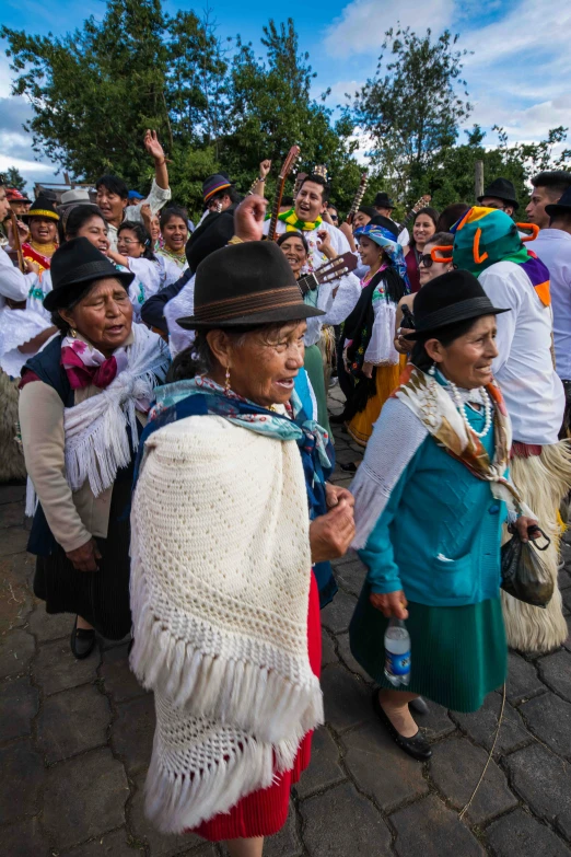 an old lady wearing a white and blue robe and with other people in bright clothes