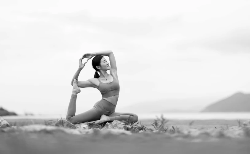 a woman doing yoga on the beach, in black and white