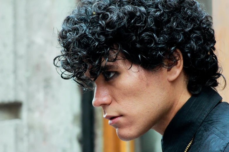 man with dark curly hair has a cigarette in his mouth