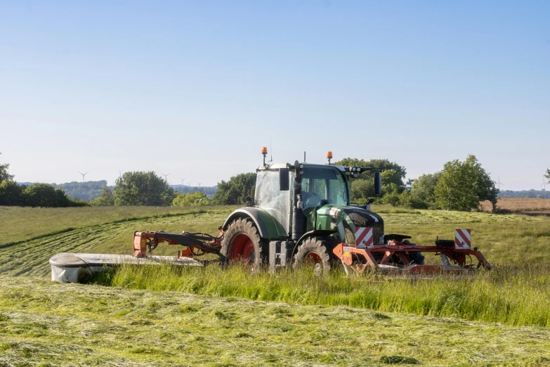 a tractor sitting in a field of grass with other equipment on the ground