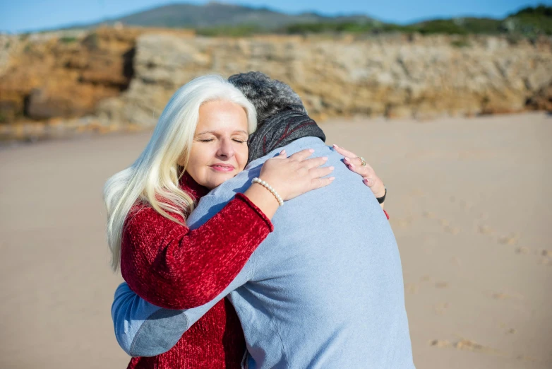 a woman holding a man in front of a mountain