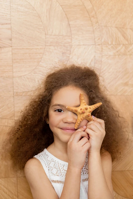 a girl holding a starfish in front of her face