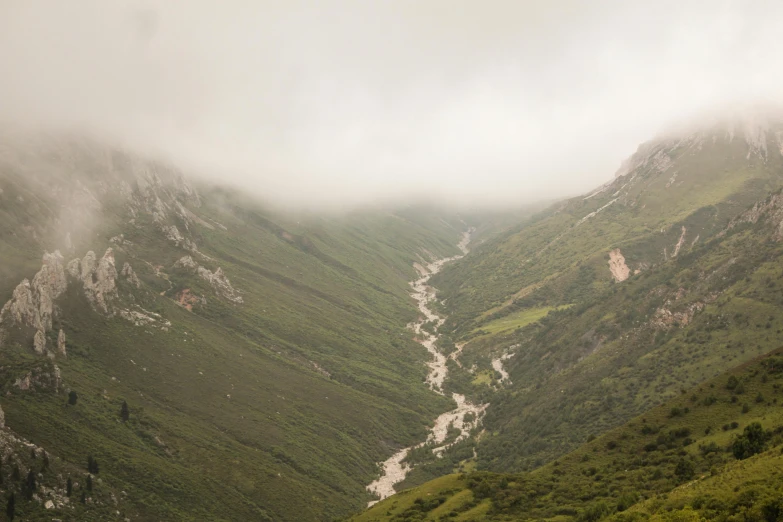 clouds cover the surrounding mountains while looking over a valley