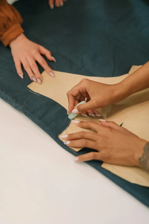 two women using a pair of scissors to attach a piece of cardboard