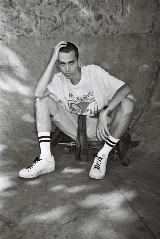 a man in a white shirt sitting on a skateboard