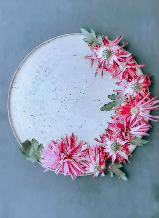 red flowers and leaves on white plate with cement