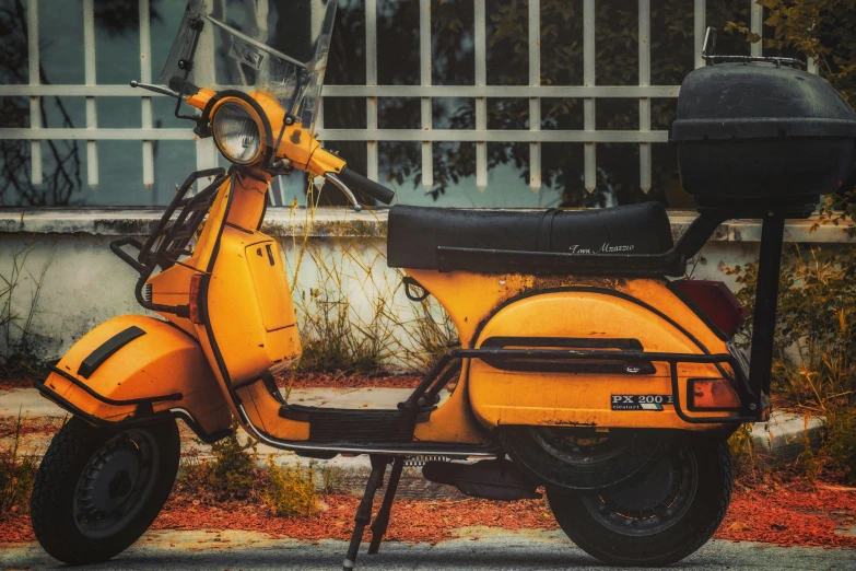 a yellow scooter parked in front of a fence