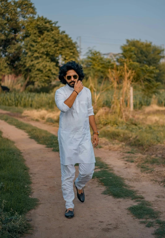 man with afro in white shirt and sunglasses on a dirt road