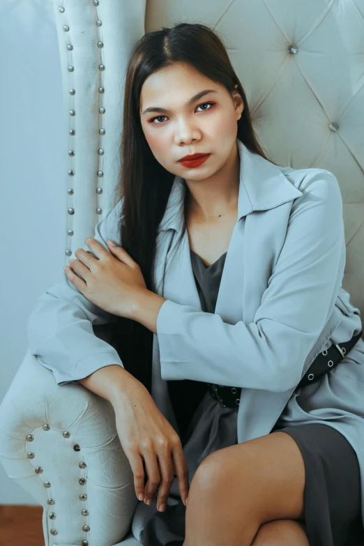 a woman in an elegant grey dress sits on a couch