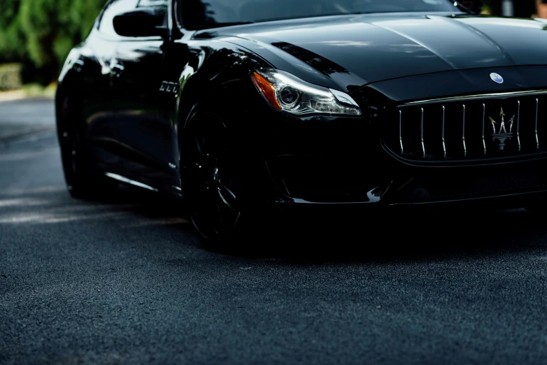 the front end of a black car is parked on the street