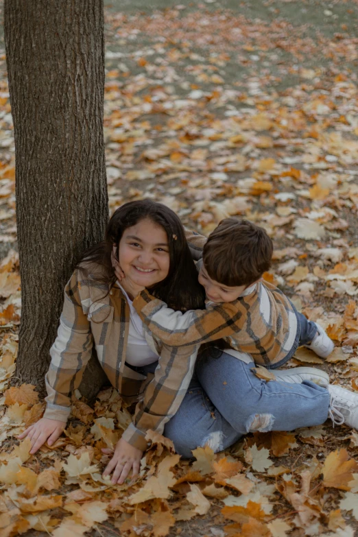 a couple is sitting underneath a tree on the ground