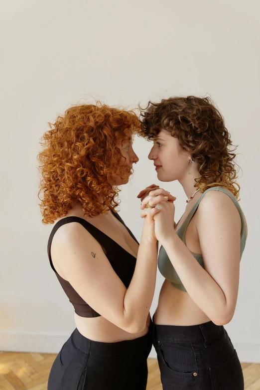 two females stand holding each other and looking at one another