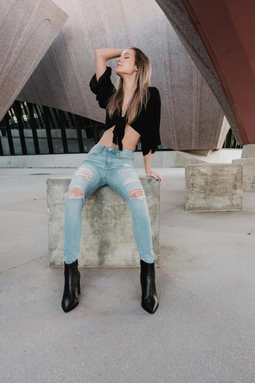 a woman in black shirt sitting on cement and posing