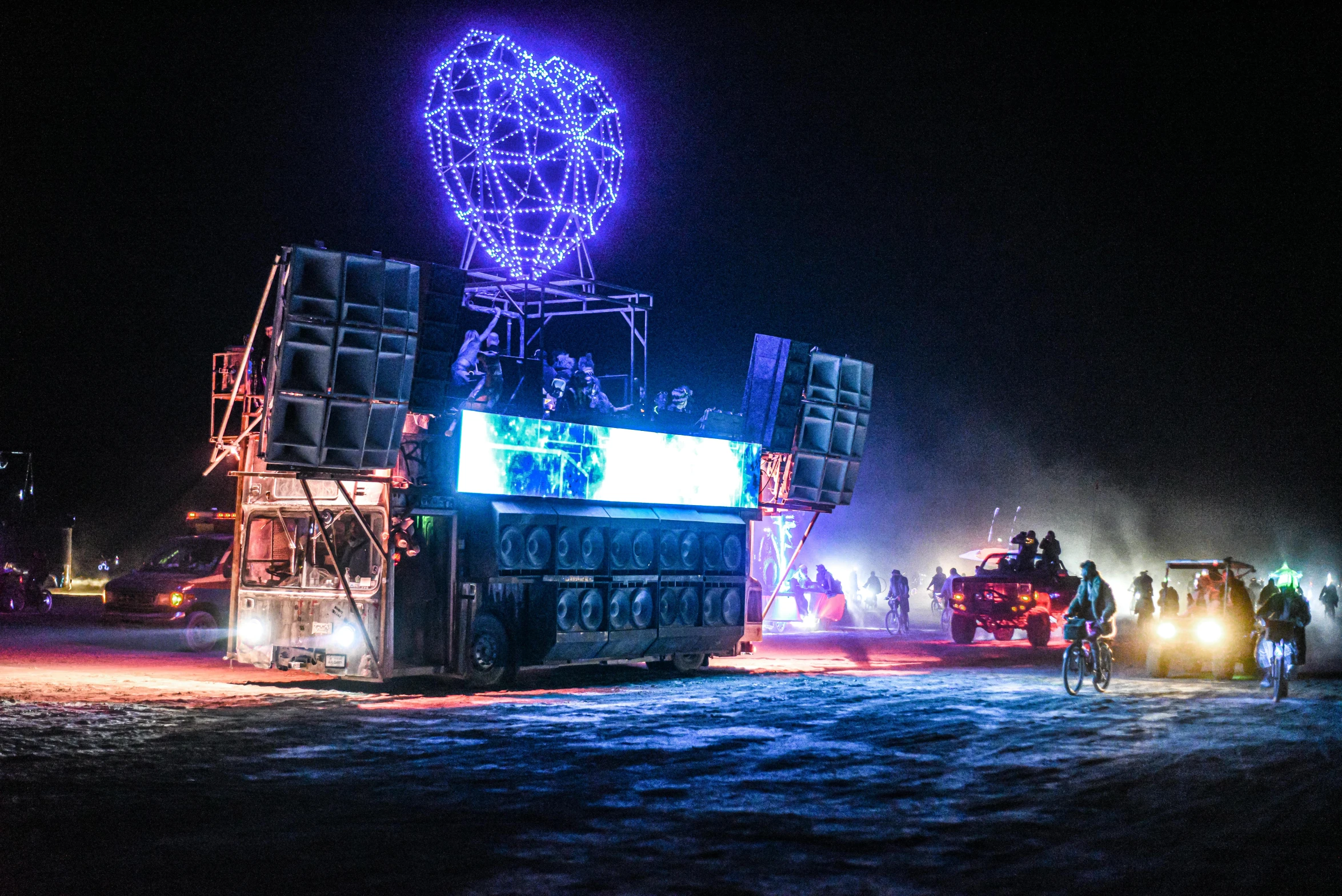 a crowd of people walk around an illuminated truck