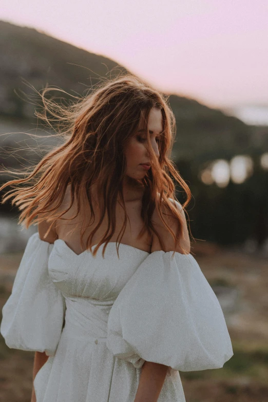 a woman in a white dress with long hair in the sun