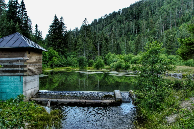 a small wooden outhouse sits next to a water source