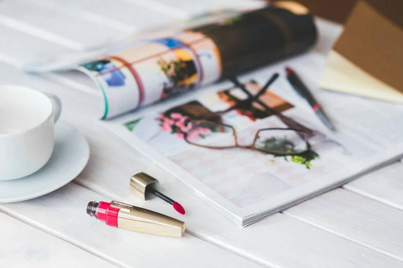 various lipsticks on a white surface and a magazine