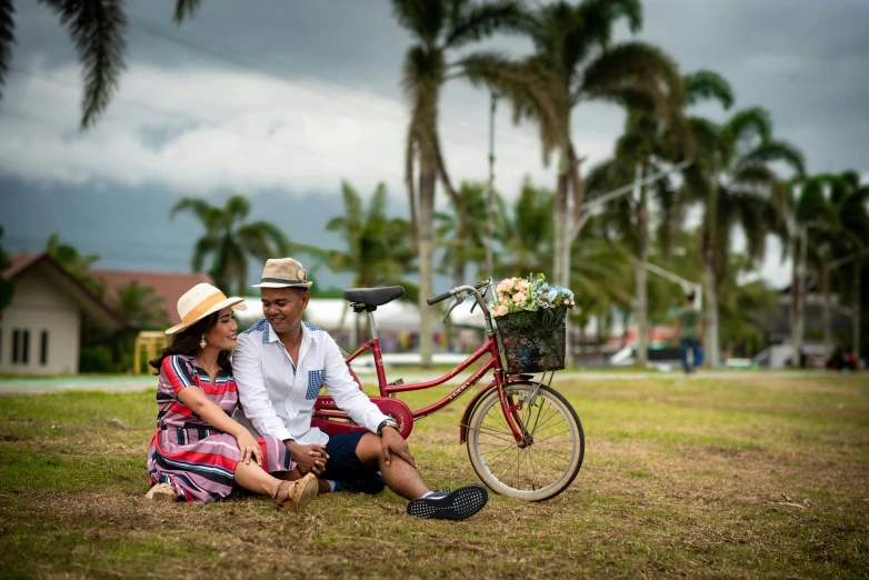 a man and a woman sit next to a bicycle