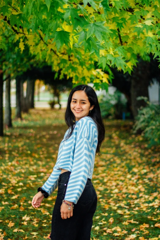 a woman standing under a green tree wearing all black