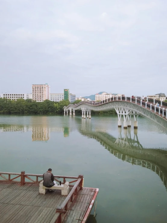 the person sits on the side of a dock looking at the water