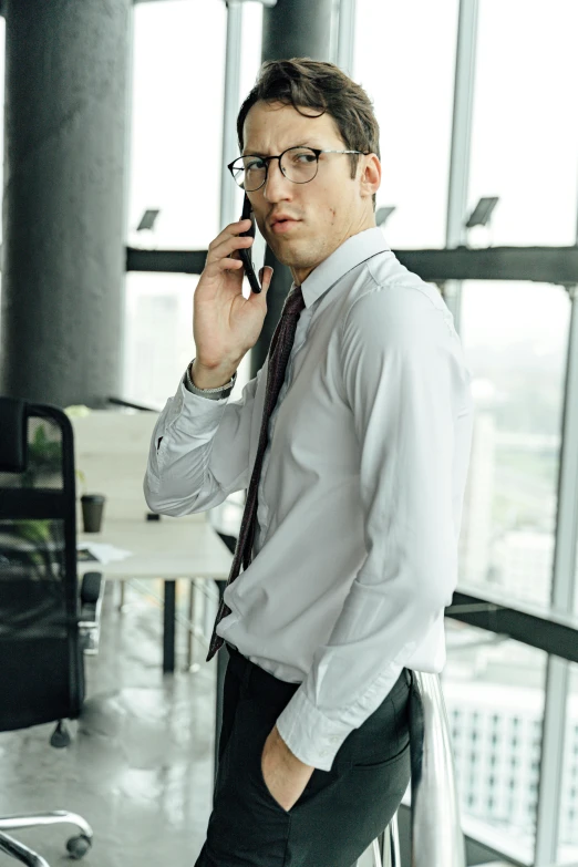 a man stands in an office lobby while on the phone