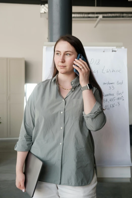 a woman stands talking on her cell phone near a white board