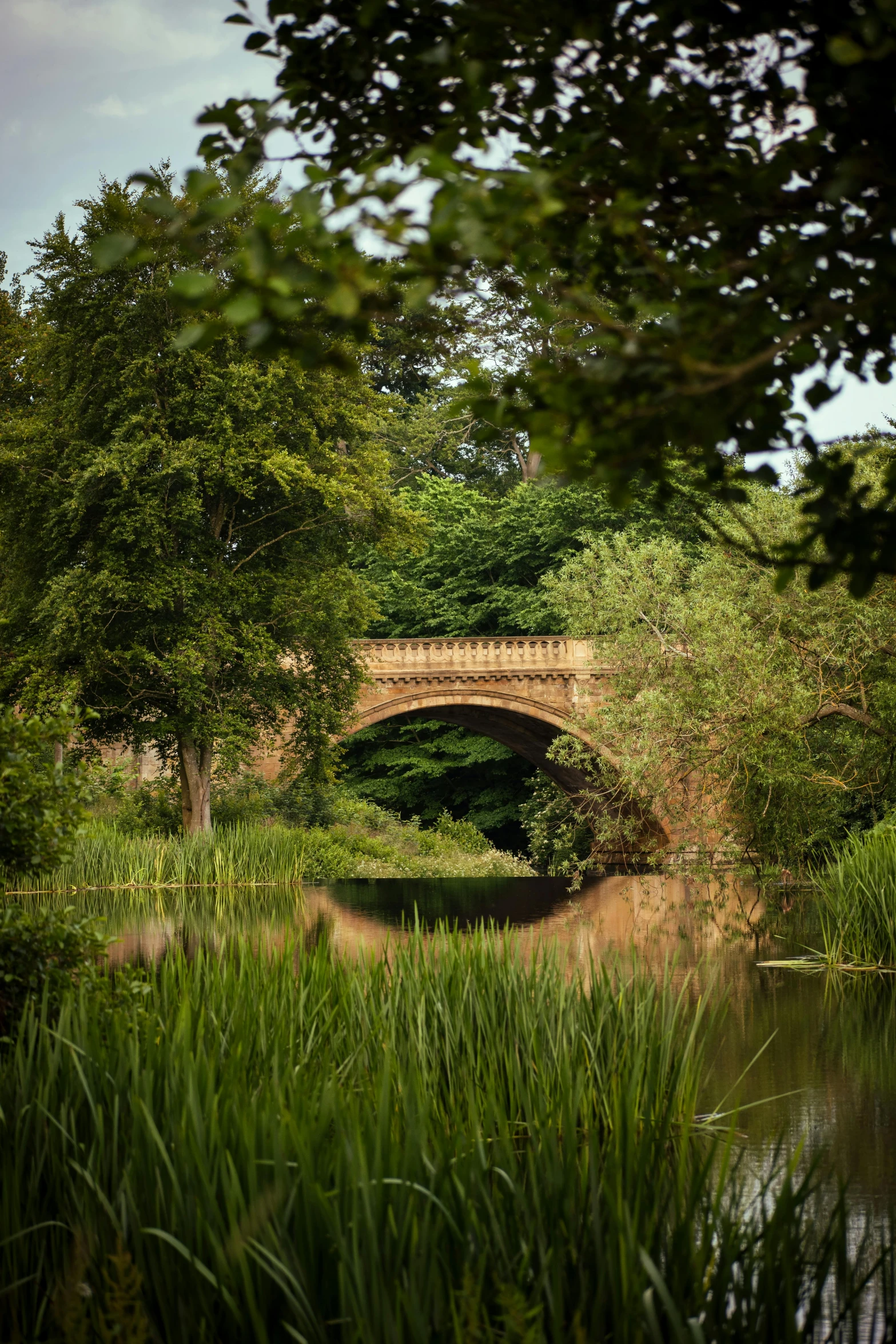 a small stone bridge spanning the width of a pond