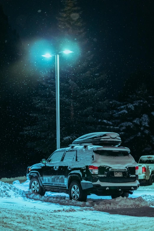 two vehicles parked in snow near the street lamp