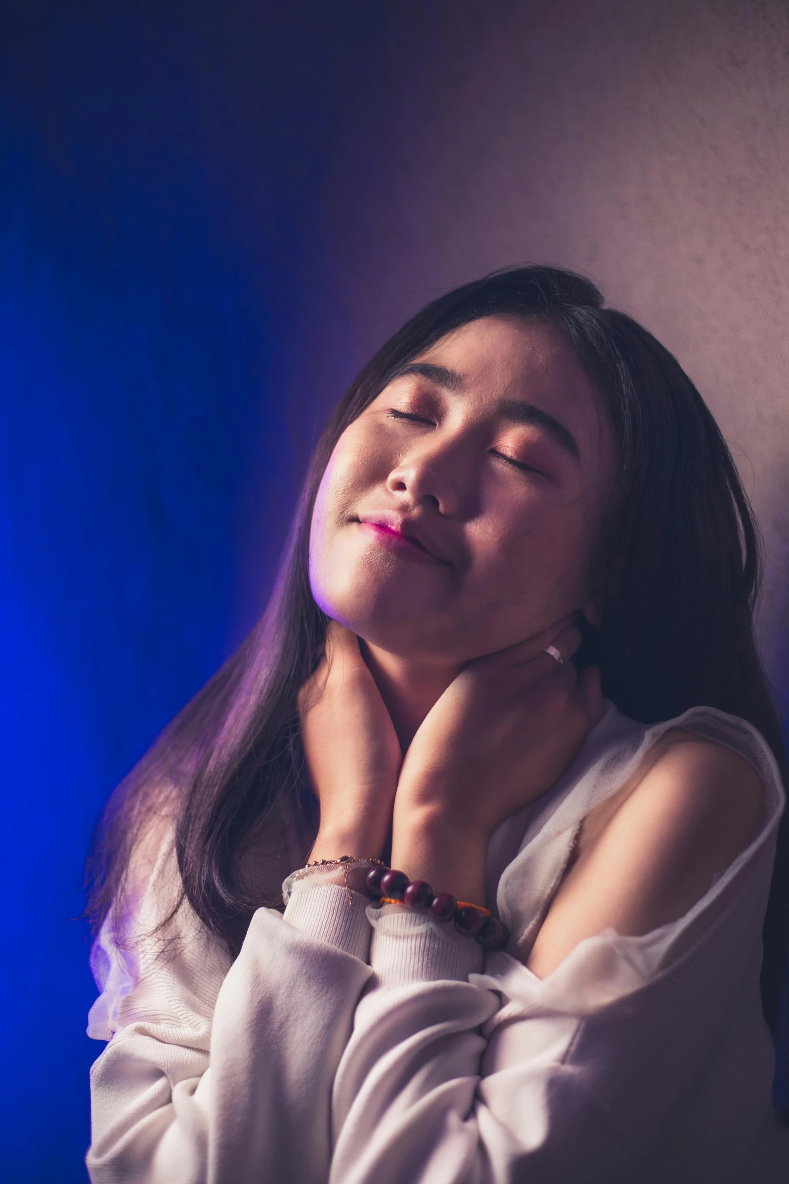 a young asian woman sitting in front of a blue background