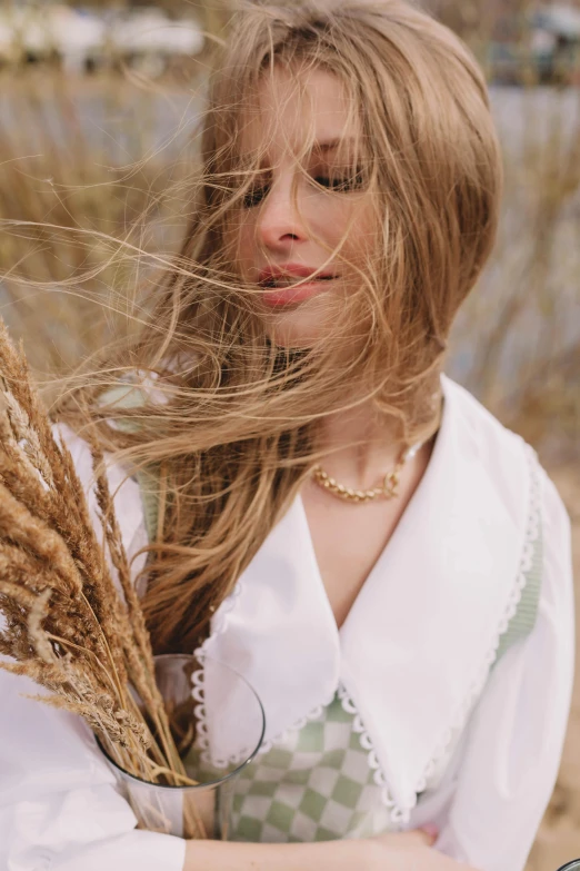 a woman holding a wheat plant with long hair