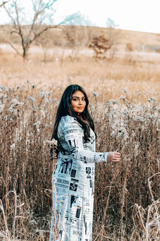 a young lady standing in a field with tall grasses